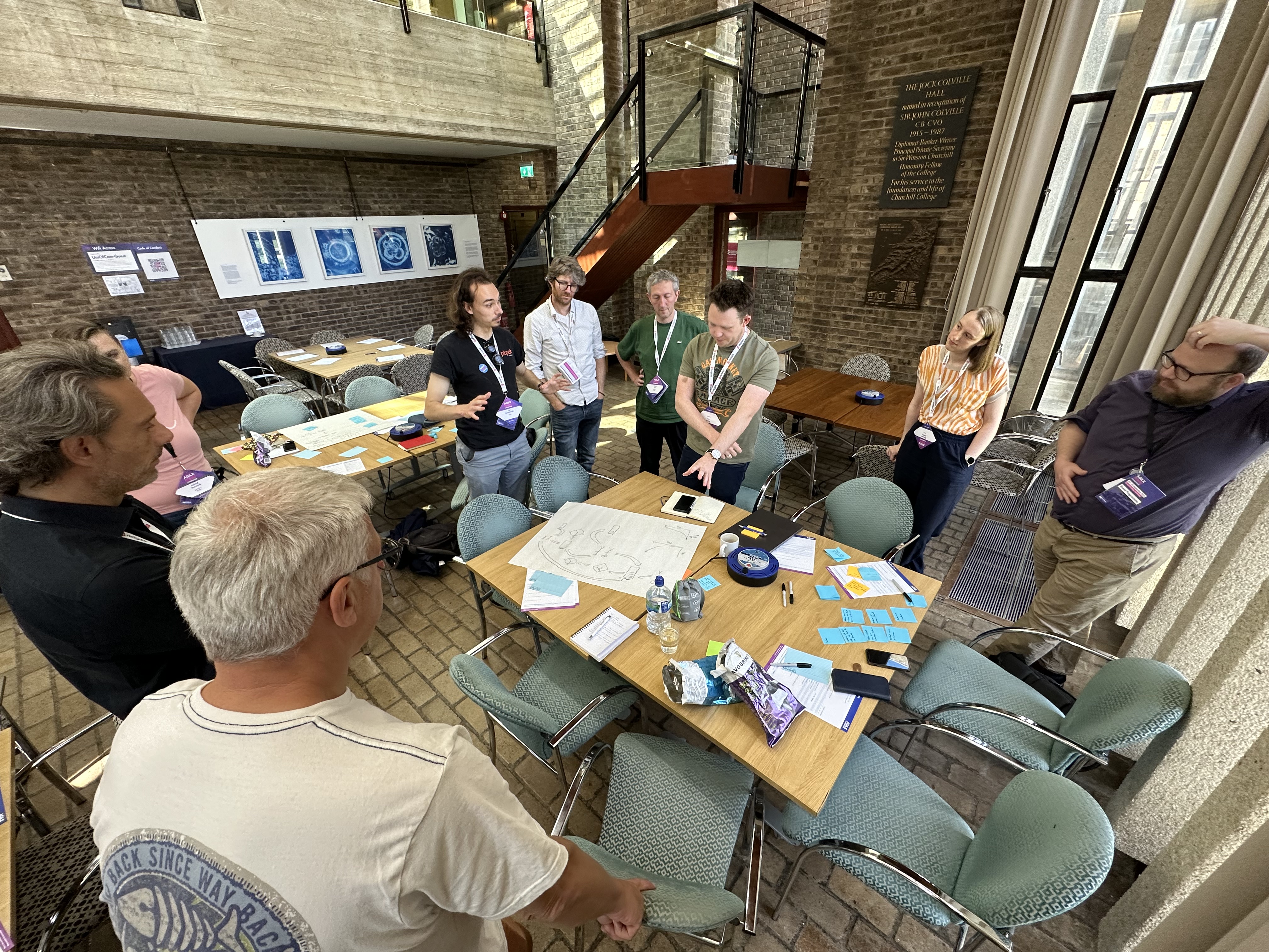 workshop participants standing around a table, discussing an example